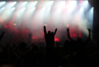 Silhouette of hand making devil horns gesture at a concert