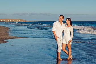 Couple in White Standing on Sandy Beach at Sunset
