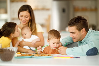 Happy family drawing and eating breakfast together in kitchen