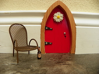 Miniature red fairy door with daisy and tiny chair