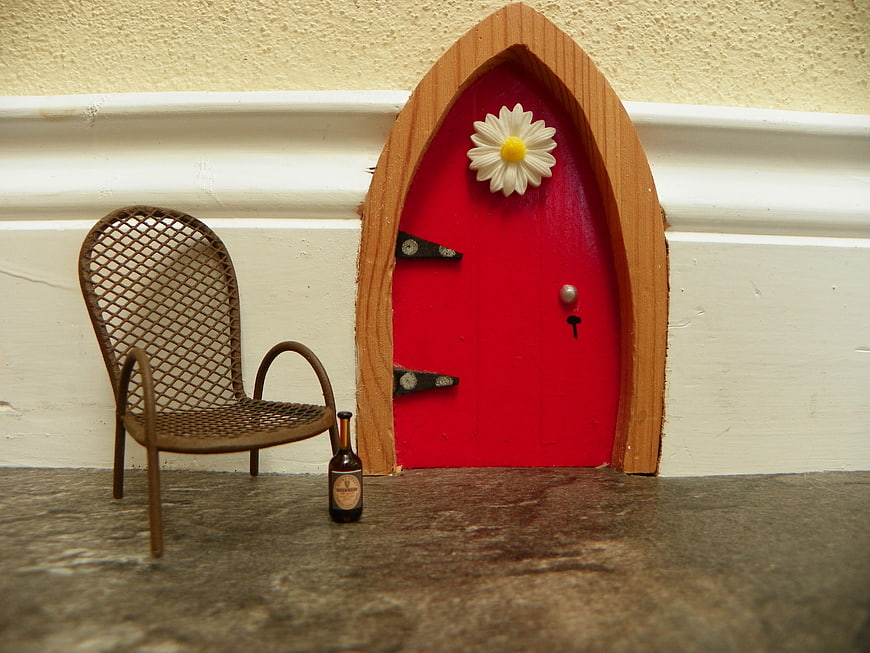 Miniature red fairy door with daisy and tiny chair