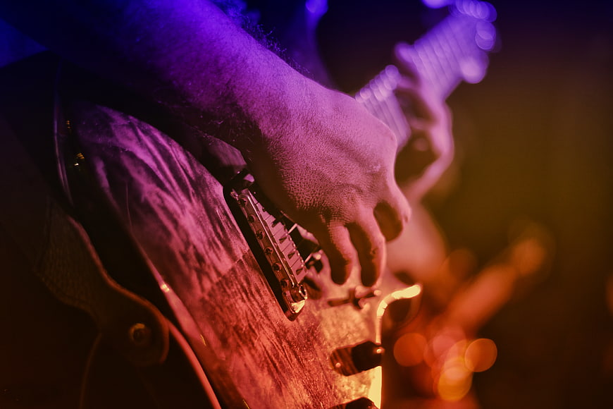 Close-up of hands playing electric guitar on stage
