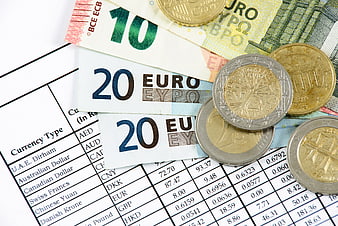Euro banknotes and coins on currency exchange rate table