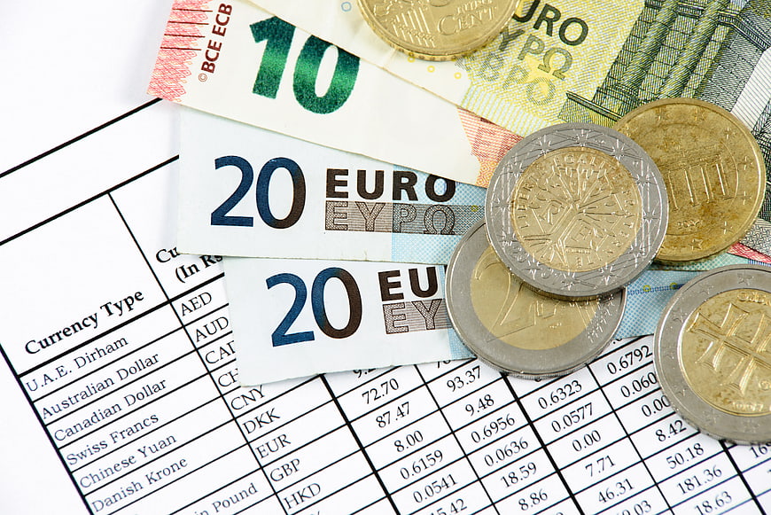 Euro banknotes and coins on currency exchange rate table