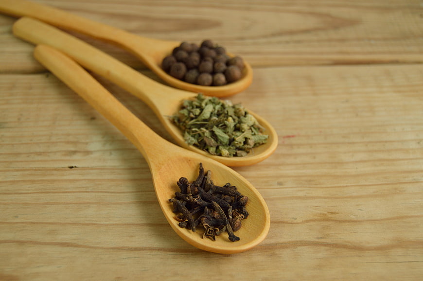 Dried spices on wooden spoons on rustic table