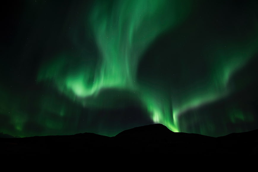 Vibrant Green Aurora Borealis Over Dark Mountain Silhouette