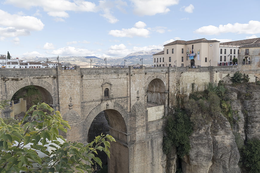 Historic stone bridge in Ronda, Spain with mountains