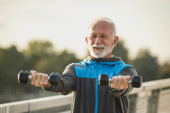 Senior man lifting dumbbells outdoors for fitness