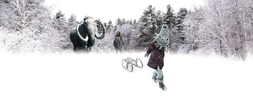 Child pulling sled in snowy forest with mammoth statue