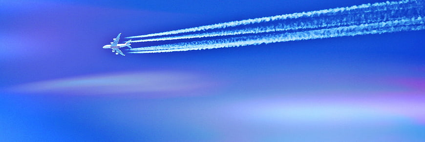 Airplane with Contrails Flying in Blue Sky