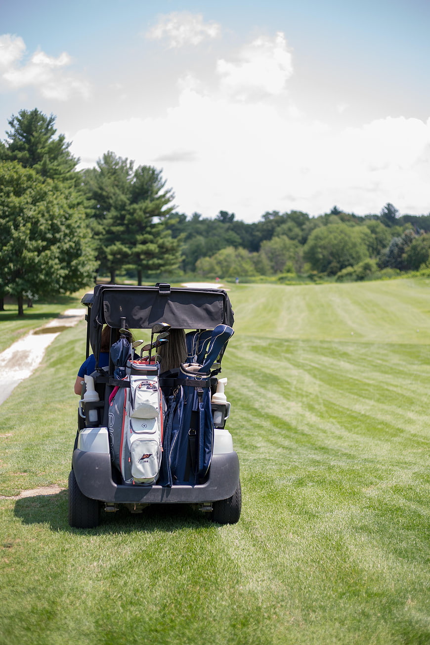 Golf cart with clubs on green course