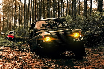 Off-road Land Rover Defender driving on muddy forest trail