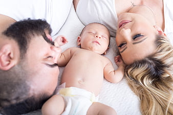 Newborn baby sleeping between parents in bed