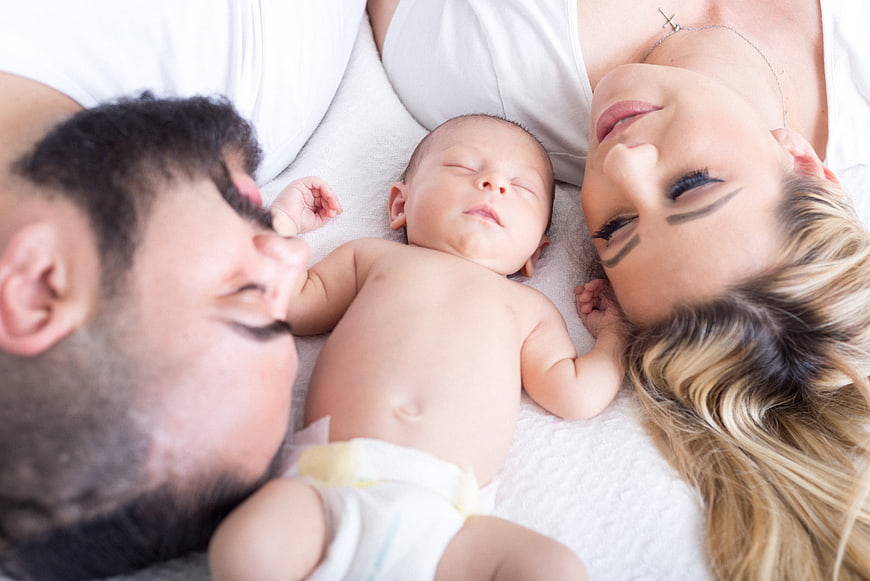 Newborn baby sleeping between parents in bed