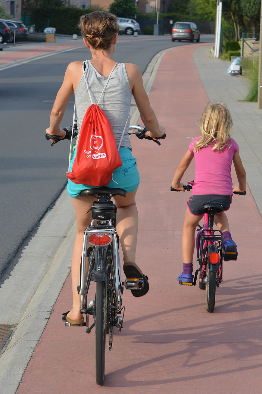 Mother and daughter cycling on a red bike path
