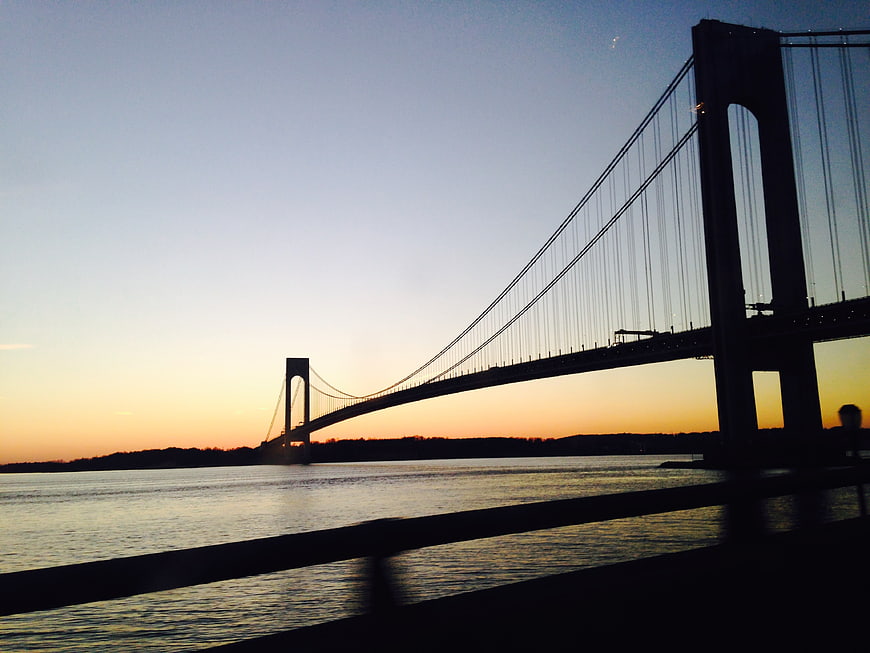 Silhouette of suspension bridge over water at sunset
