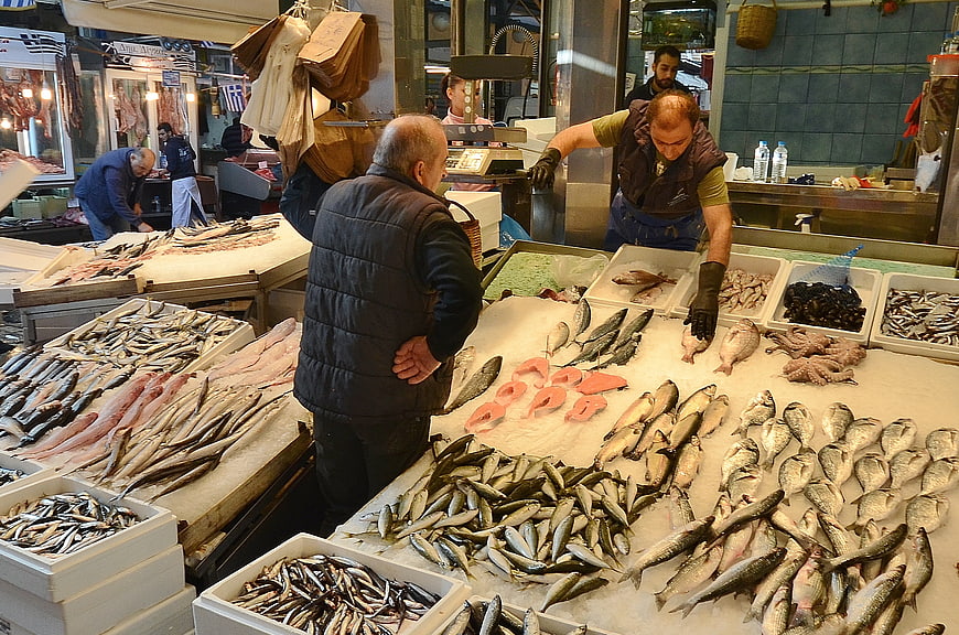 Fresh seafood market stall with fishmonger and customer