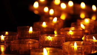 Glowing tea light candles in glass holders with warm bokeh background