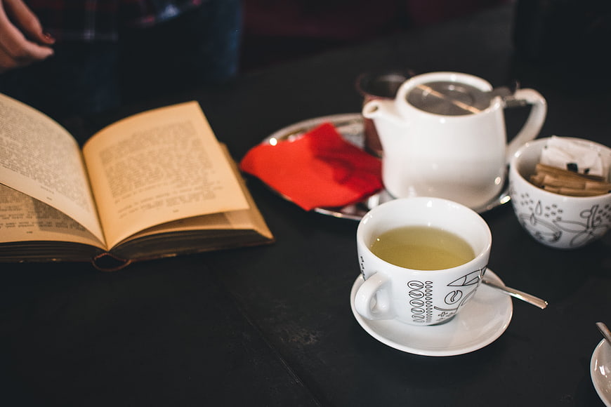 Open book and green tea on dark cafe table