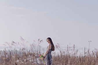 Woman in Dress Holding Flowers in Winter Field