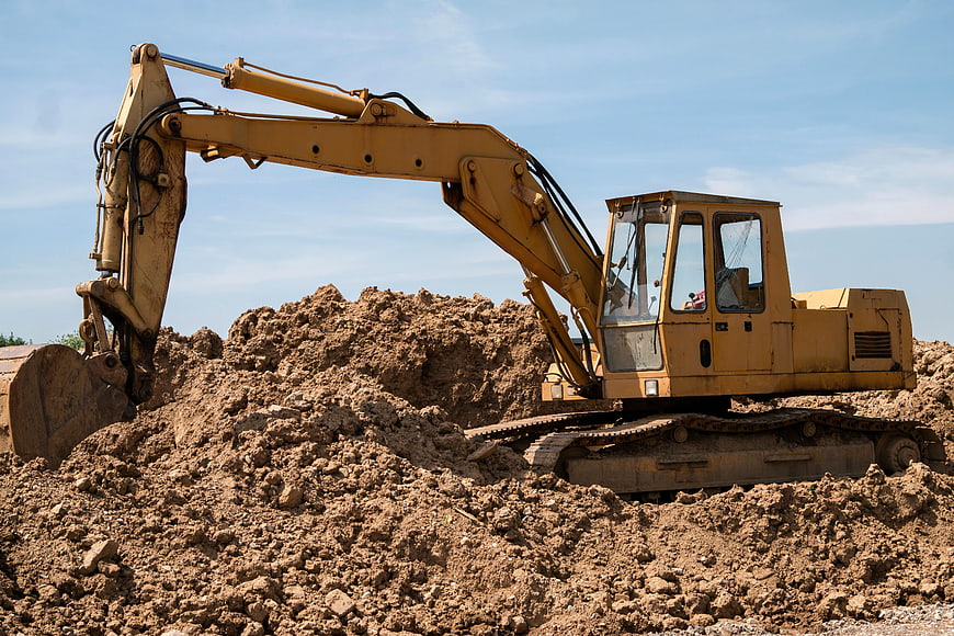 Yellow Excavator Digging Dirt at Construction Site