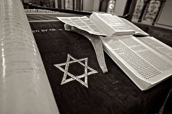 Sepia toned Star of David on Torah scroll and open Hebrew prayer book