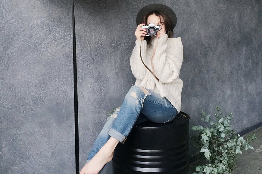 Woman Photographer Sitting on Barrel with Vintage Camera