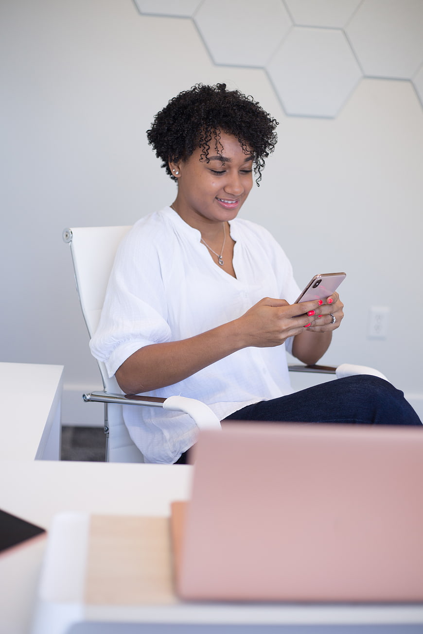Smiling woman using smartphone in modern office