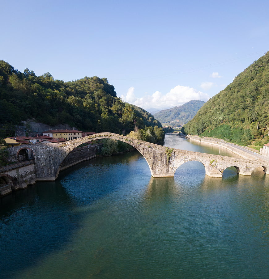 Historic stone arch bridge over river in Italian valley