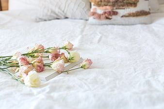 Pink and white flowers on a book on a white bed