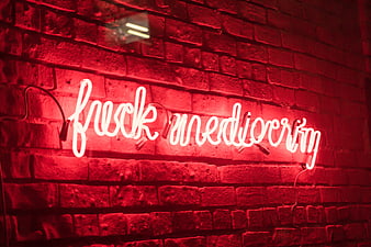 Red neon sign with motivational quote on brick wall