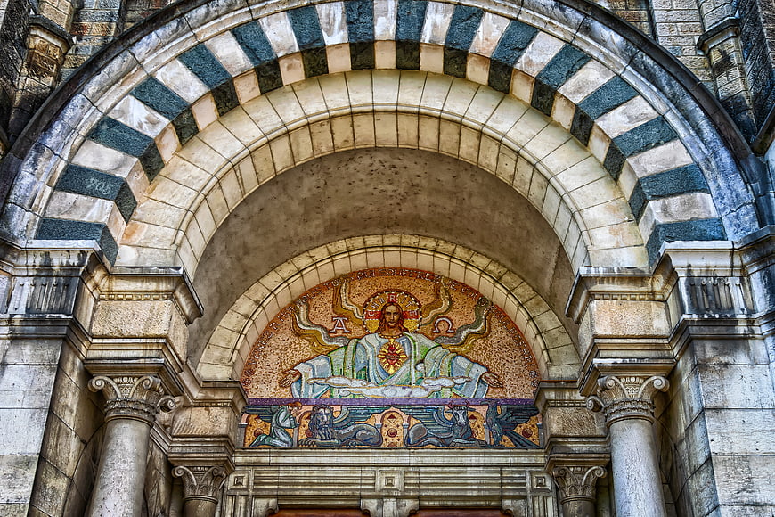 Historic Cathedral Facade With Striped Arch And Religious Mosaic
