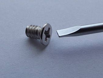 Flathead Screwdriver Tip Mismatched With Phillips Screw On Gray Surface