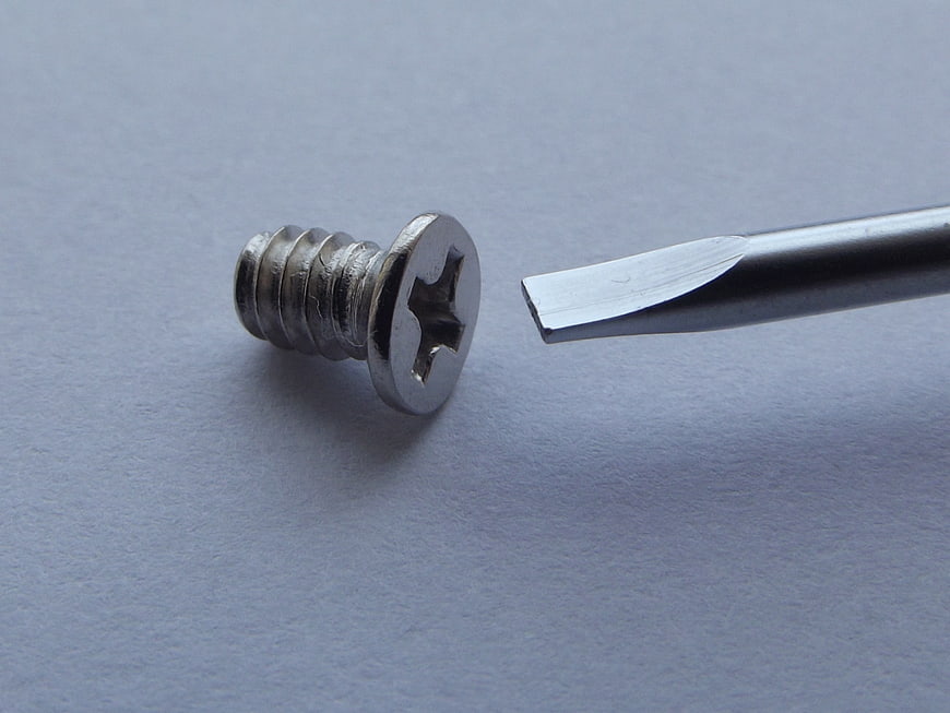 Flathead Screwdriver Tip Mismatched With Phillips Screw On Gray Surface
