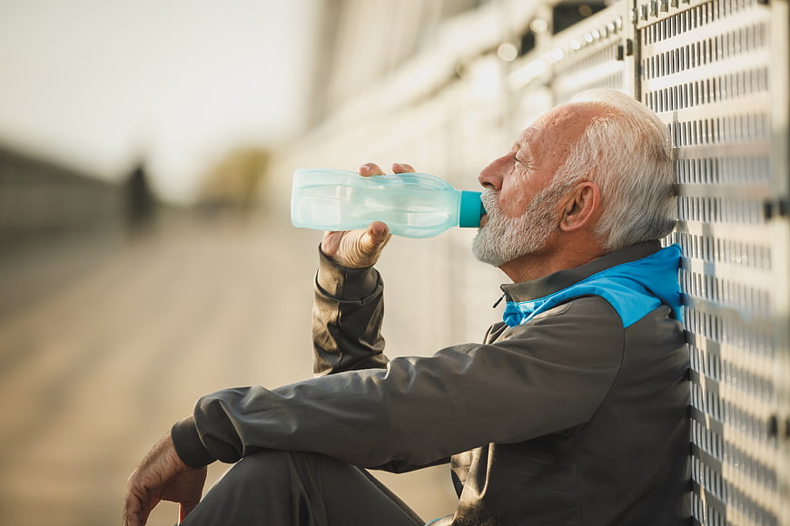 Senior man drinking water after outdoor workout
