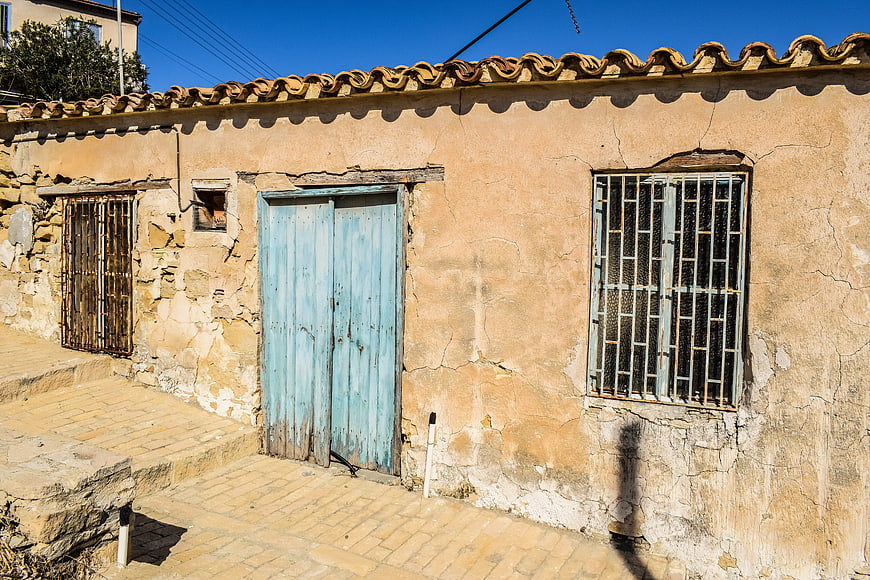 Old rustic house with blue door and barred windows