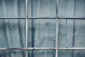 Textured gray window with peeling white grid and translucent curtain