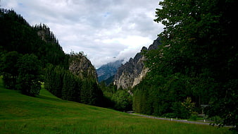 Scenic Alpine Valley with Green Hills and Rocky Peaks