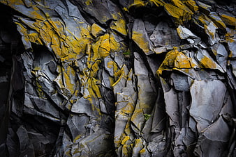 Textured Rock Wall with Yellow Lichen and Gray Stone Crevices