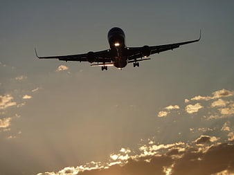 Silhouette of Airplane Landing Against Golden Sunset Sky