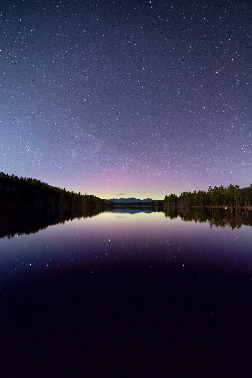 Starry Night Sky Reflection on Calm Lake with Forest