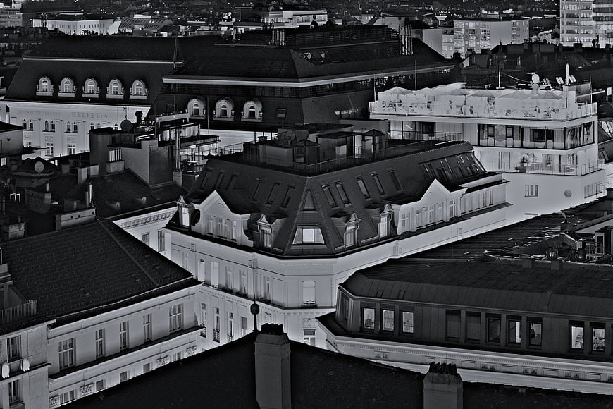 Black and white aerial view of European city rooftops at night