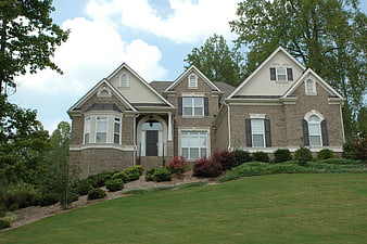 Modern two-story brick house with green lawn and trees
