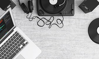 Top view of laptop, turntable, and headphones on gray desk