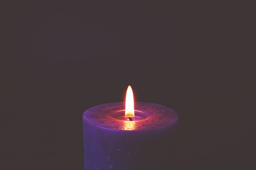 Purple Candle Burning in Dark Room with Flame