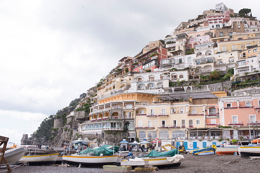 Colorful cliffside village with boats on pebble beach