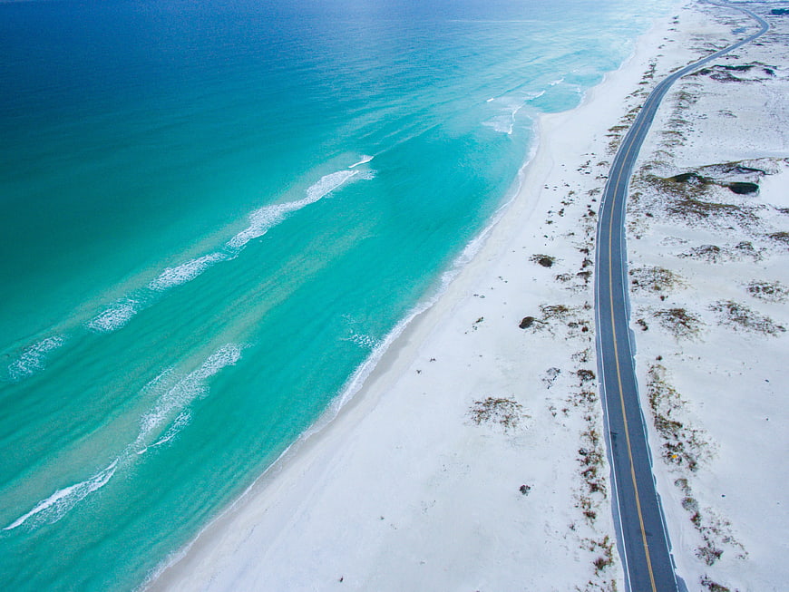 Aerial View of Coastal Highway Along Turquoise Ocean Beach