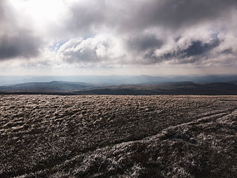 Frosty moorland landscape with dramatic cloudy sky and distant mountains