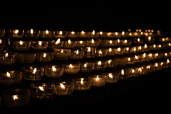 Rows of lit tea light candles in a dark church setting