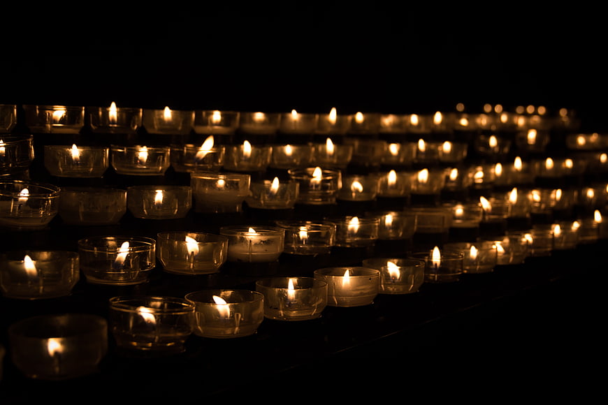 Rows of lit tea light candles in a dark church setting